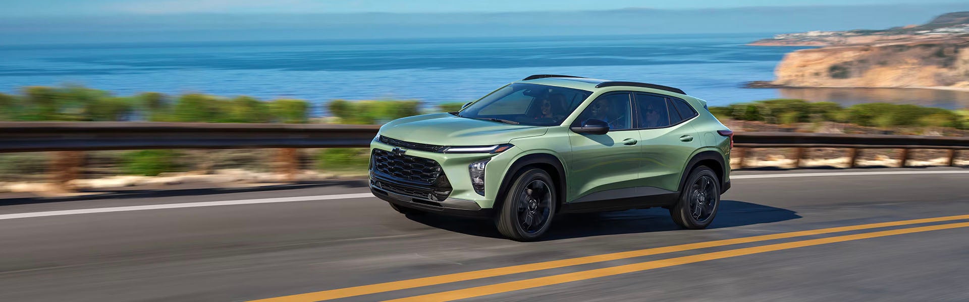 2025 Chevrolet Trax driving on a rural road in front of a lake