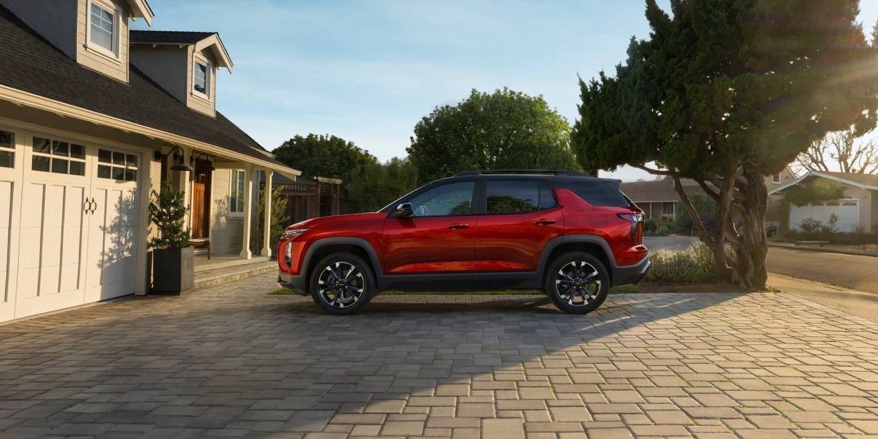 2025 Chevrolet Equinox in red side view parked on a cobblestone driveway