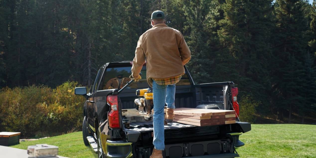 man strapping down lumber and tools in the bed of his 2025 Chevrolet Silverado