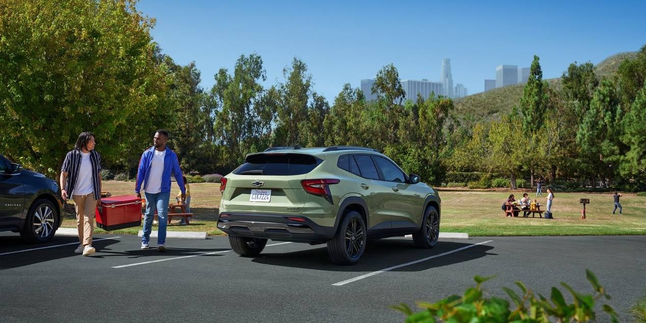 couple parked in a park and carrying a red cooler to their 2025 Chevrolet Trax