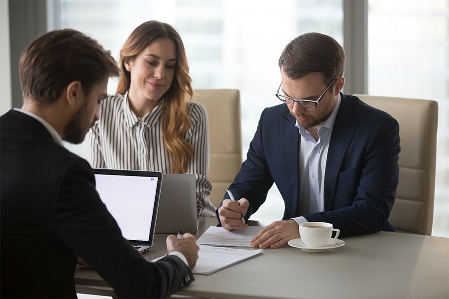 couple signing paperwork with car salesman